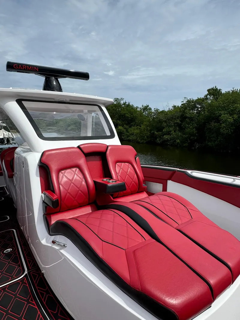 Slide: The Image of Luxury red seating on 2022 Deep Impact 399 boat, surrounded by lush greenery. - 37