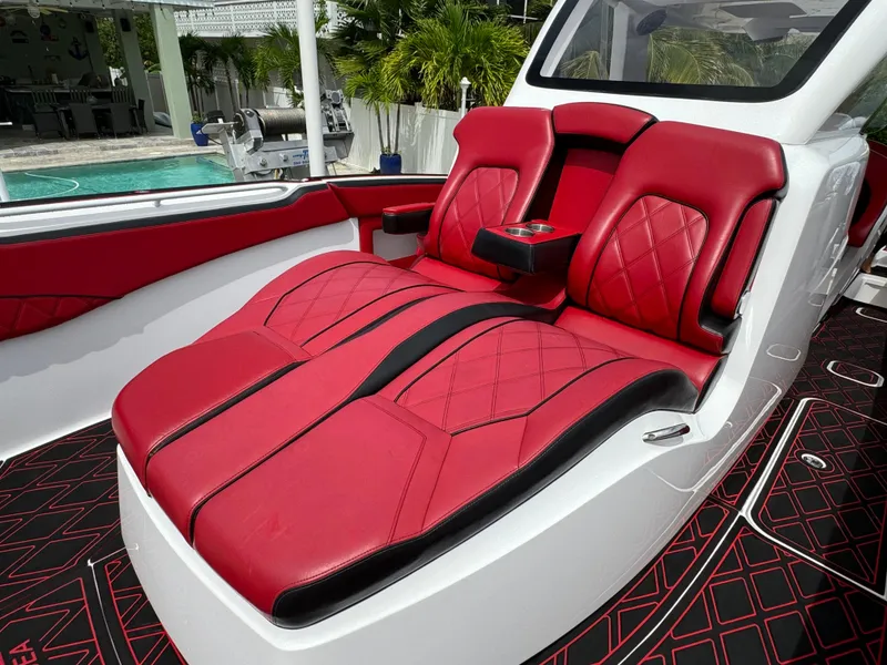 Slide: The Image of Luxurious red and black seating on 2022 Deep Impact 399 boat, near a poolside setting. - 38
