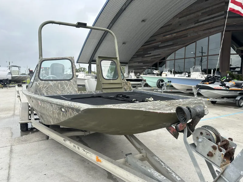 Slide: The Image of Custom 2004 model 23 boat on trailer at marina, camouflage design, parked near other boats. - 8