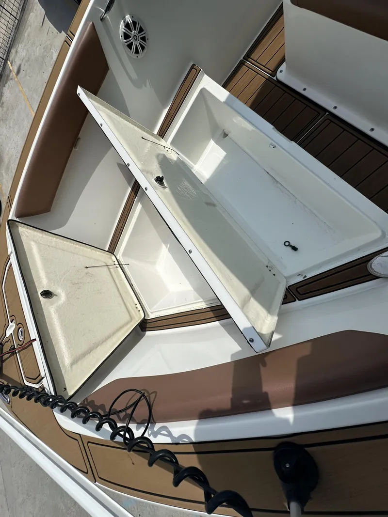 Slide: The Image of 2019 Clearwater 2300 boat with open storage compartments and brown seating. - 15