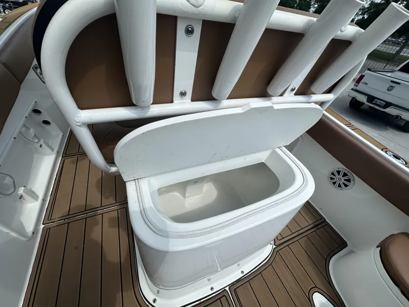 Slide: The Image of Open storage compartment on a 2019 Clearwater 2300 boat with rod holders and teak flooring. - 5