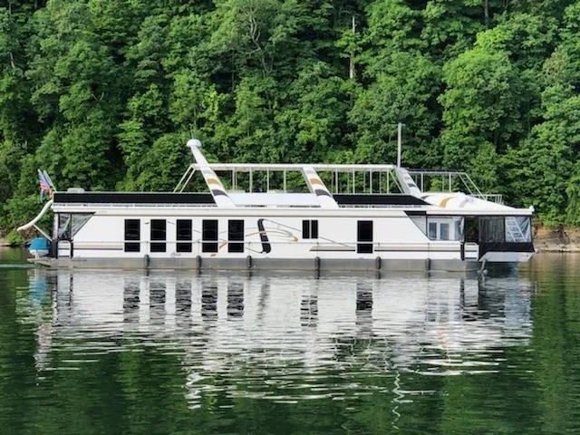 The Image of 2005 Fantasy Houseboat 19x90 on a serene lake with lush green forest backdrop. - 0