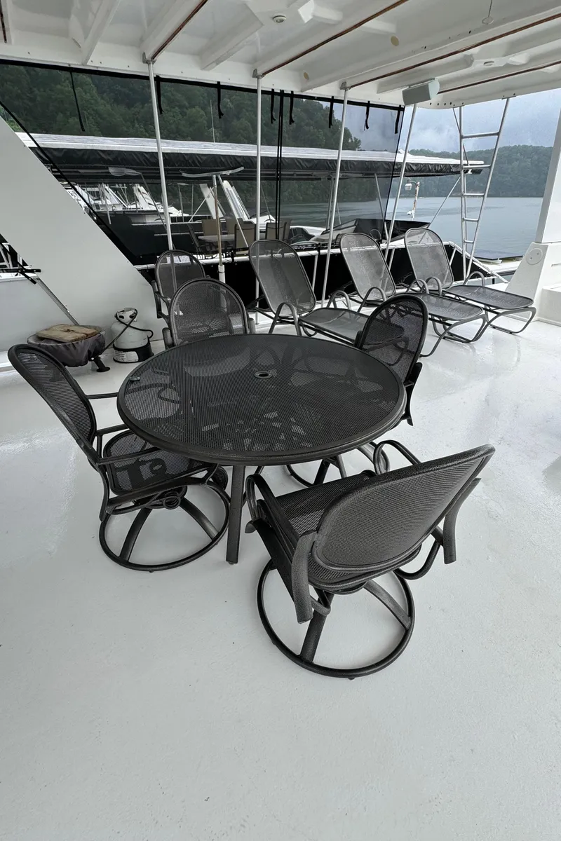 Slide: The Image of Spacious deck of 2005 Fantasy Houseboat 19x90 with seating and grills, docked by a scenic lake. - 10