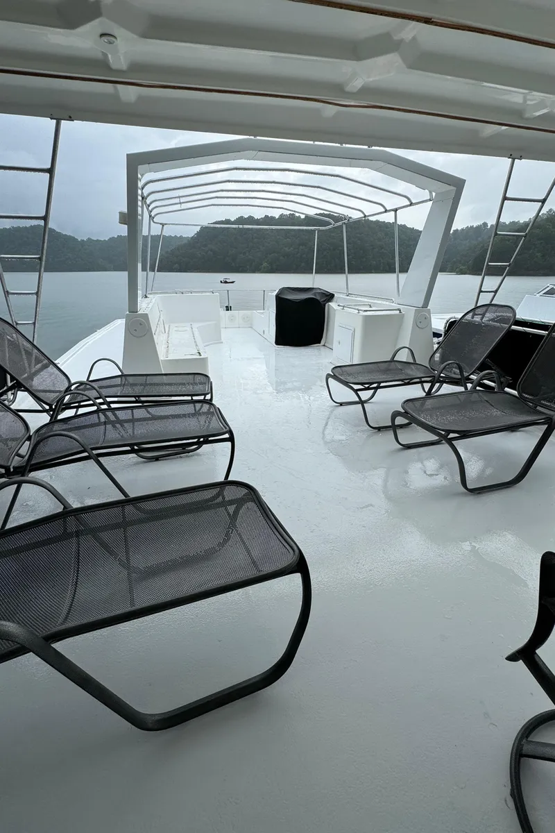Slide: The Image of 2005 Fantasy Houseboat 19x90 with spacious deck, scenic lake view, and outdoor kitchen setup. - 11