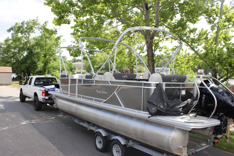 Slide: The Image of 2021 SunChaser Geneva Cruise 24 SB pontoon boat on trailer, towed by a white truck. - 32