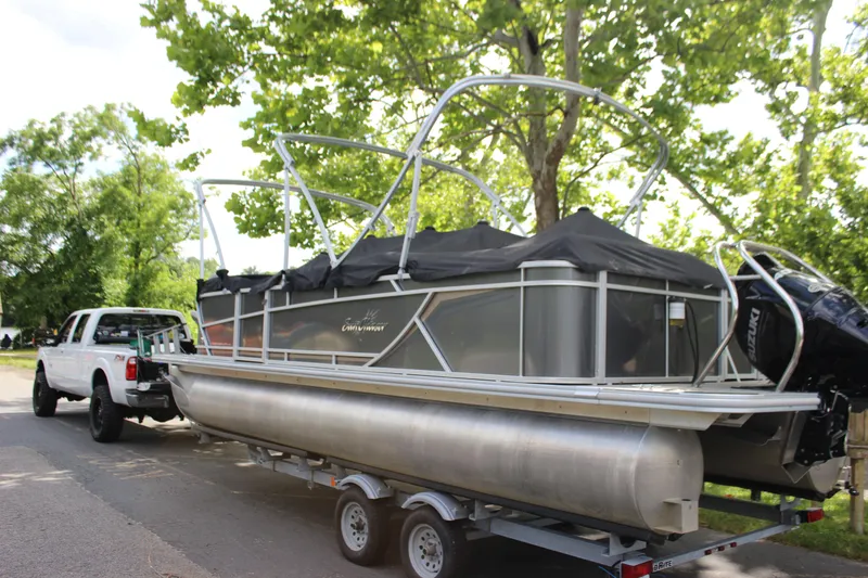 Slide: The Image of 2021 SunChaser Geneva Cruise 24 SB pontoon boat on trailer, towed by a white truck. - 36