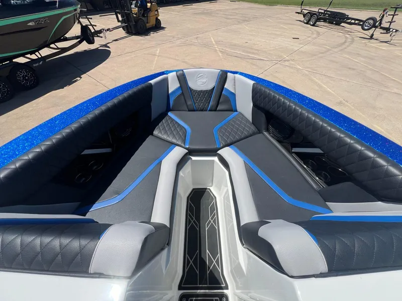 Slide: The Image of 2023 Tigé 25ZX boat interior with blue and gray seating, parked on concrete. - 14