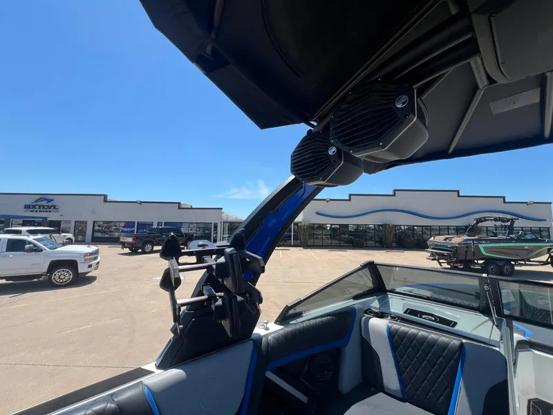 Slide: The Image of 2023 Tigé 25ZX boat interior with speakers, parked at a dealership under clear blue sky. - 15