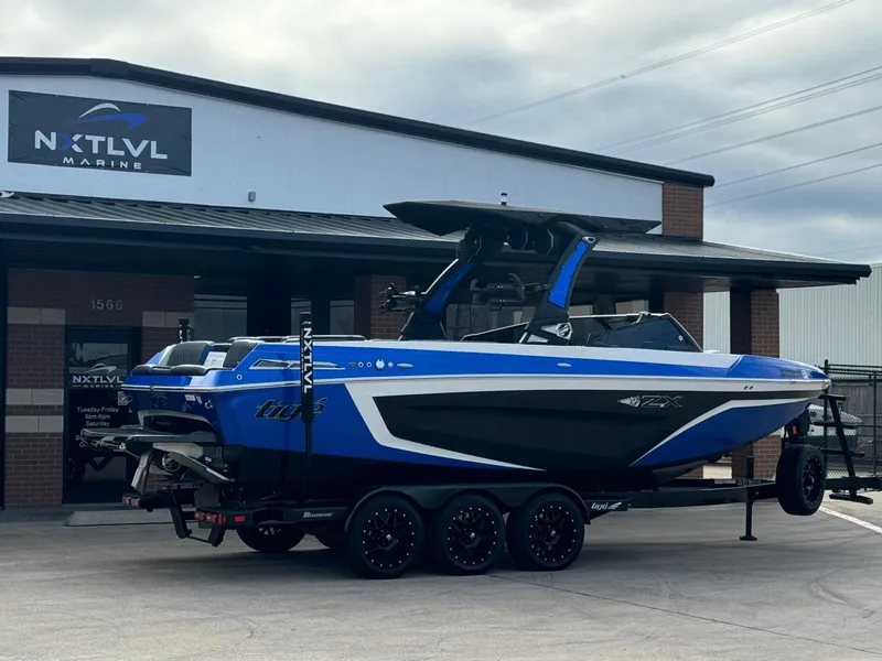 Slide: The Image of 2023 Tigé 25ZX boat in blue on trailer at NXT LVL Marine dealership. - 4