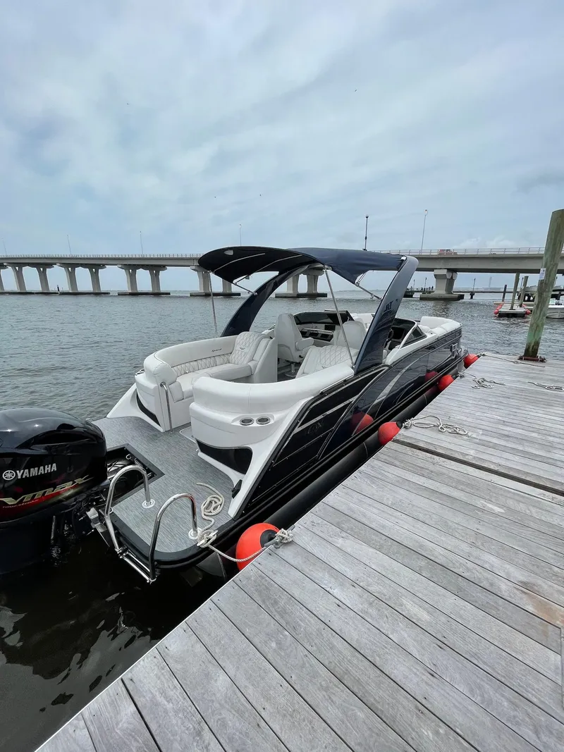 Slide: The Image of 2021 Bennington QX 25 QXFBWA Fastback pontoon boat docked by a pier. - 2