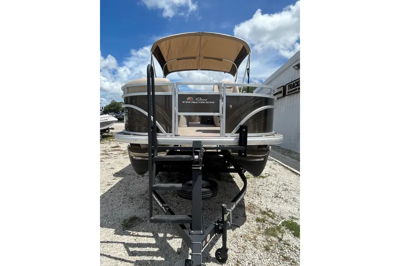 Slide: The Image of 2024 Sun Tracker SportFish 20 DLX pontoon boat with canopy, parked on gravel. - 3