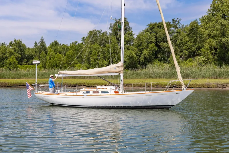 Slide: The Image of 2005 Morris M36 sailboat on a calm lake with lush green trees in the background. - 0