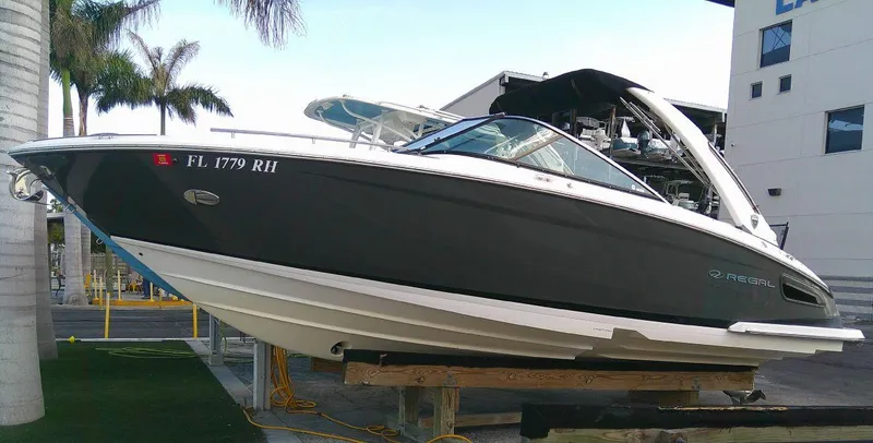 Slide: The Image of 2017 Regal 2800 Bowrider boat on a lift, docked near palm trees. - 5