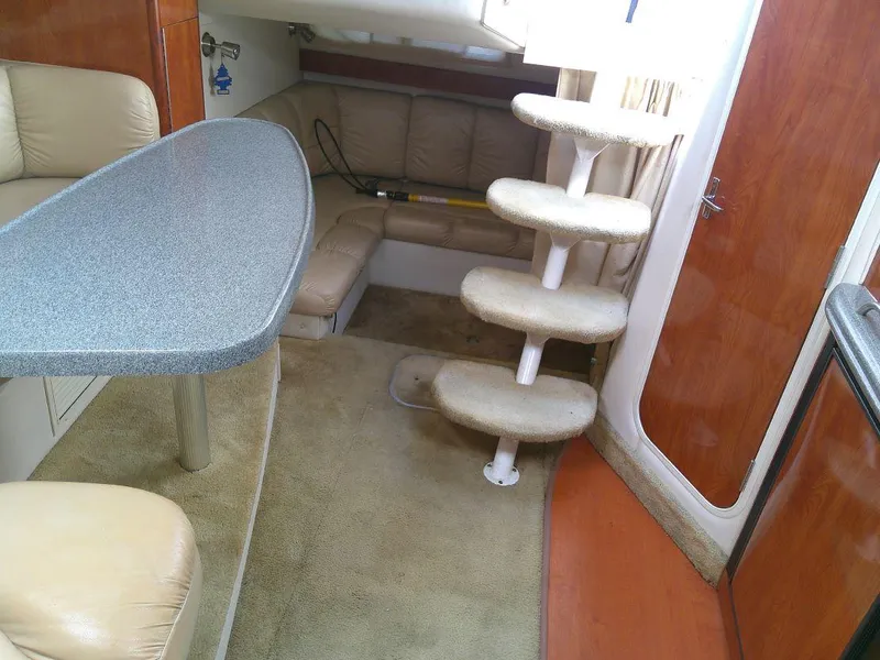 Slide: The Image of 2005 Larson Cabrio 330 cabin interior with seating, table, and stairs. - 22