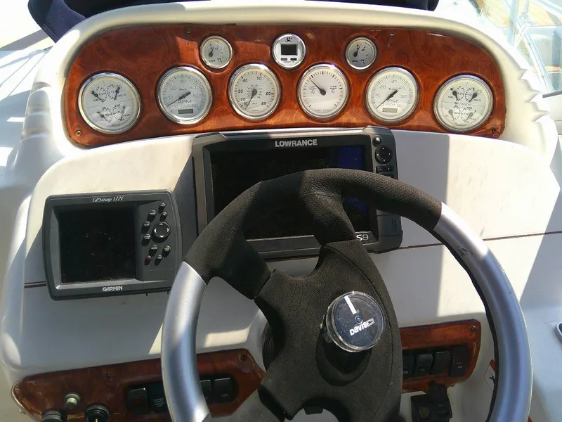 Slide: The Image of 2005 Larson Cabrio 330 boat dashboard with steering wheel and navigation instruments. - 27