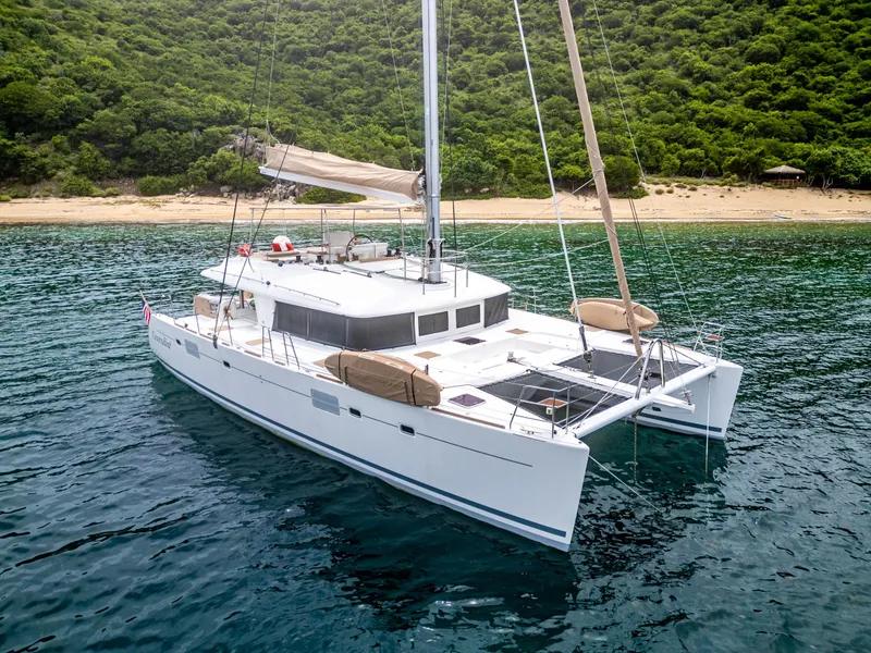 Slide: The Image of Luxurious 2012 Lagoon 560 catamaran anchored near a lush, tropical shoreline. - 0