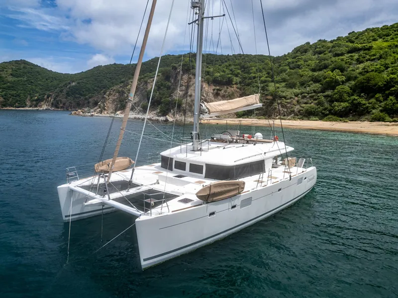 Slide: The Image of Luxurious 2012 Lagoon 560 catamaran anchored in a scenic bay with lush green hills. - 12