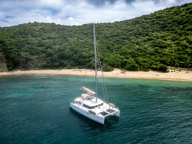Slide: The Image of Lagoon 560 catamaran anchored near a lush, green island coastline, 2012 model. - 13