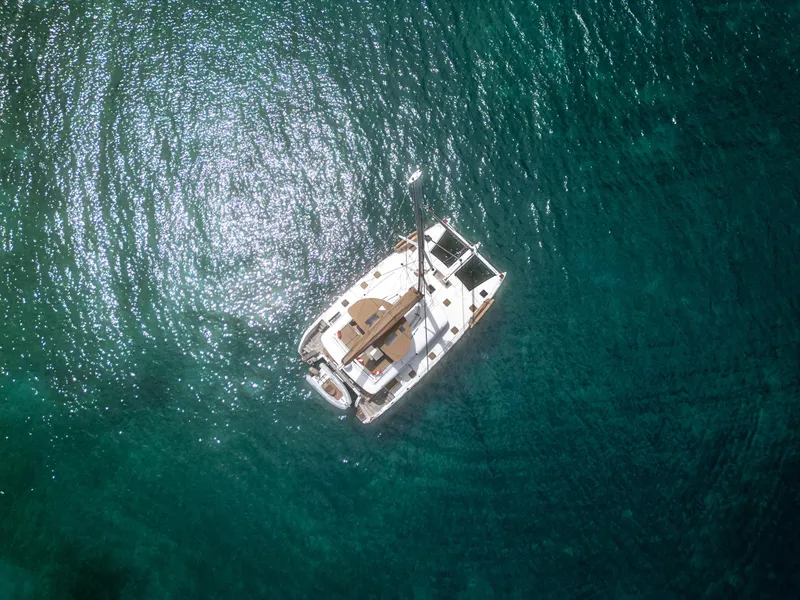 Slide: The Image of Aerial view of 2012 Lagoon 560 catamaran on clear turquoise water. - 15