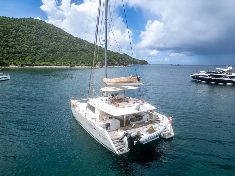 Slide: The Image of Lagoon 560 catamaran sailing in a serene bay, 2012 model, with lush green hills in the background. - 17