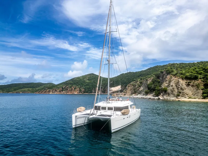 Slide: The Image of Lagoon 560 catamaran anchored in scenic bay, 2012 model, with lush hills and clear blue sky. - 19