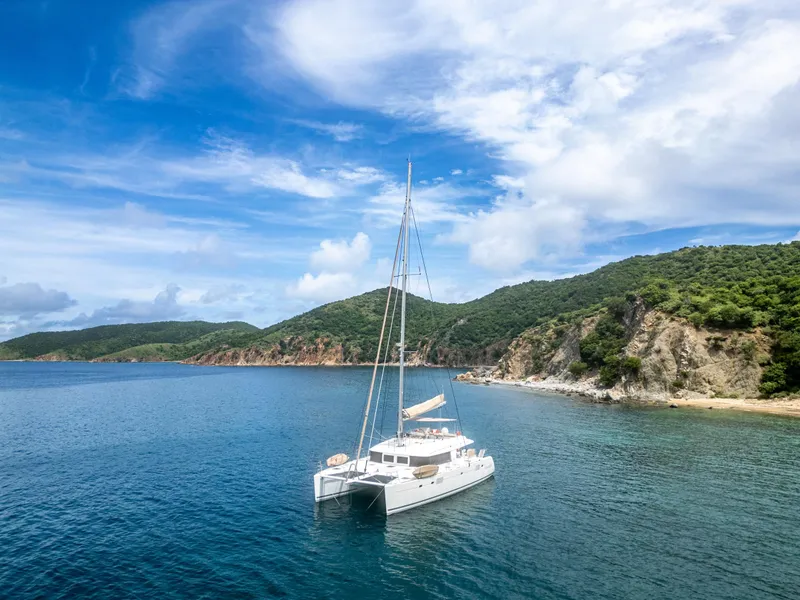 Slide: The Image of Lagoon 560 catamaran anchored in a serene bay with lush hills, 2012 model. - 20