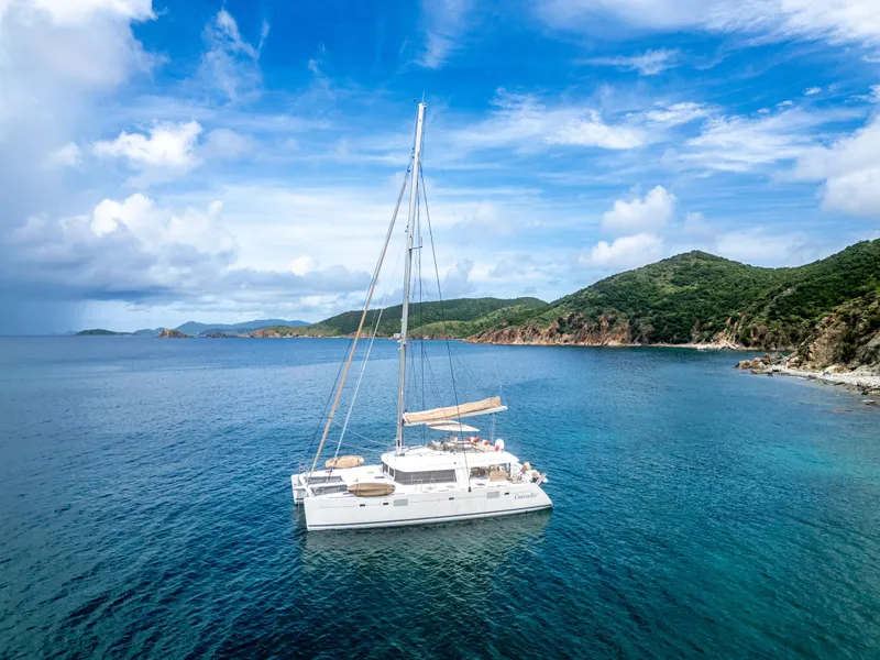 Slide: The Image of Lagoon 560 catamaran sailing near lush coastline under a vibrant blue sky, 2012 model. - 21