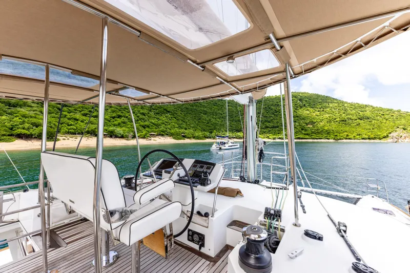 Slide: The Image of Luxurious 2012 Lagoon 560 yacht cockpit with scenic ocean and lush green island backdrop. - 28