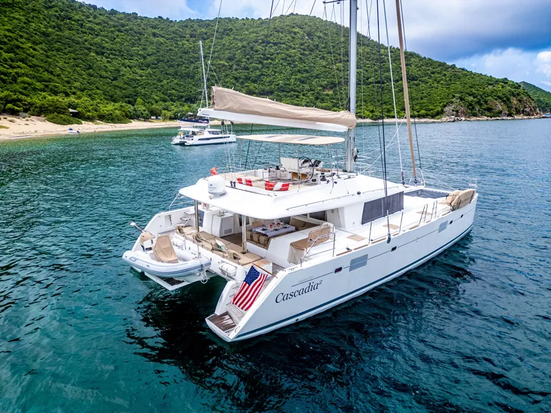 Slide: The Image of Lagoon 560 catamaran, 2012 model, anchored in scenic bay with lush green hills. - 3