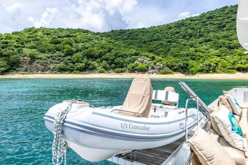 Slide: The Image of Lagoon 560 yacht with dinghy, anchored near lush green island, 2012 model. - 43