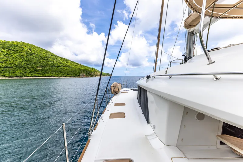 Slide: The Image of Lagoon 560 yacht sailing near lush green island under blue sky, 2012 model. - 44