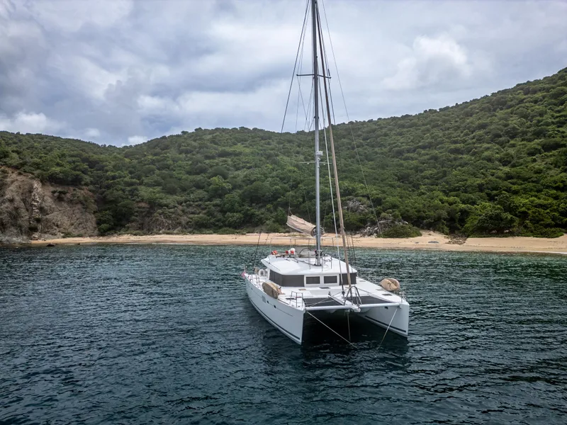 Slide: The Image of Lagoon 560 catamaran anchored near a lush, green island coastline, 2012 model. - 9
