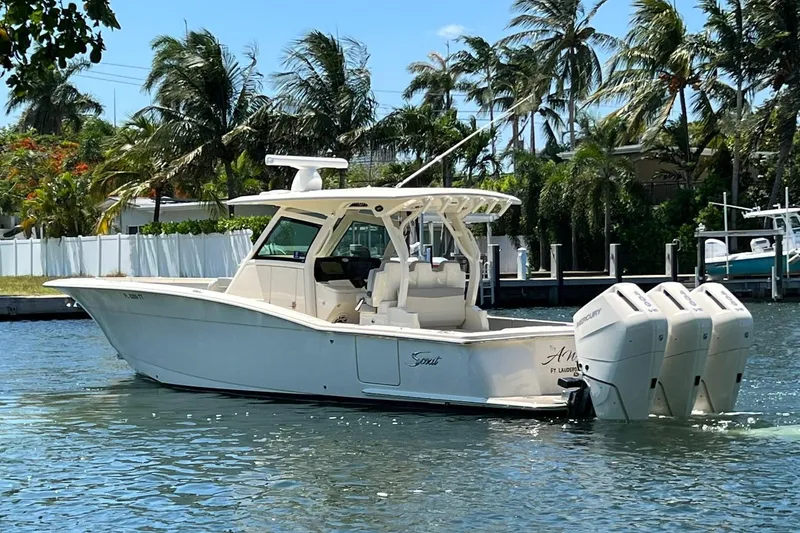 Slide: The Image of 2024 Scout 355 LXF boat cruising on a sunny day with palm trees in the background. - 1