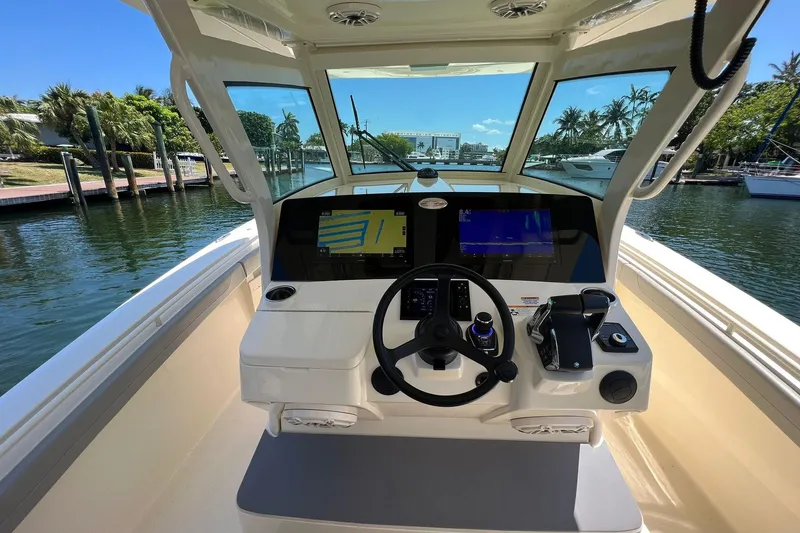 Slide: The Image of 2024 Scout 355 LXF boat helm with dual screens and waterfront view. - 10
