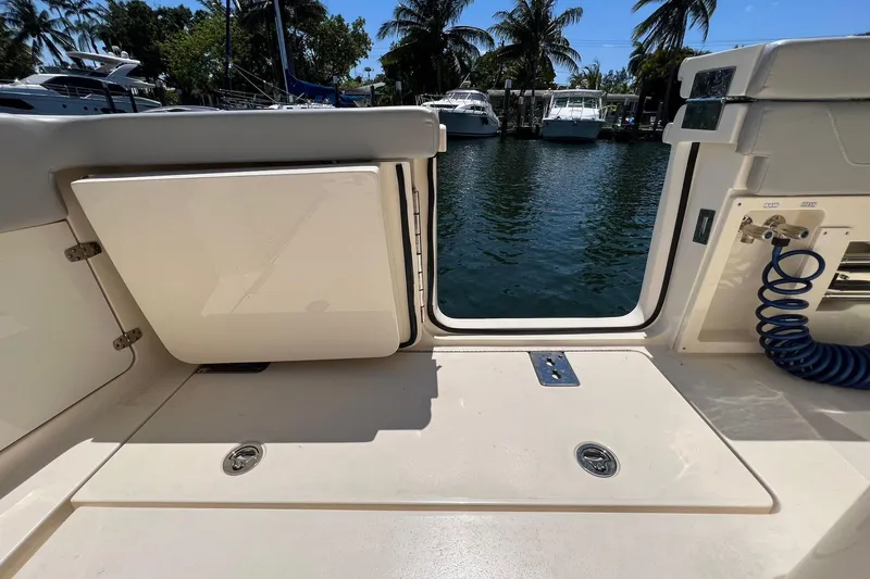 Slide: The Image of 2024 Scout 355 LXF boat deck with open hatch and water view. - 12