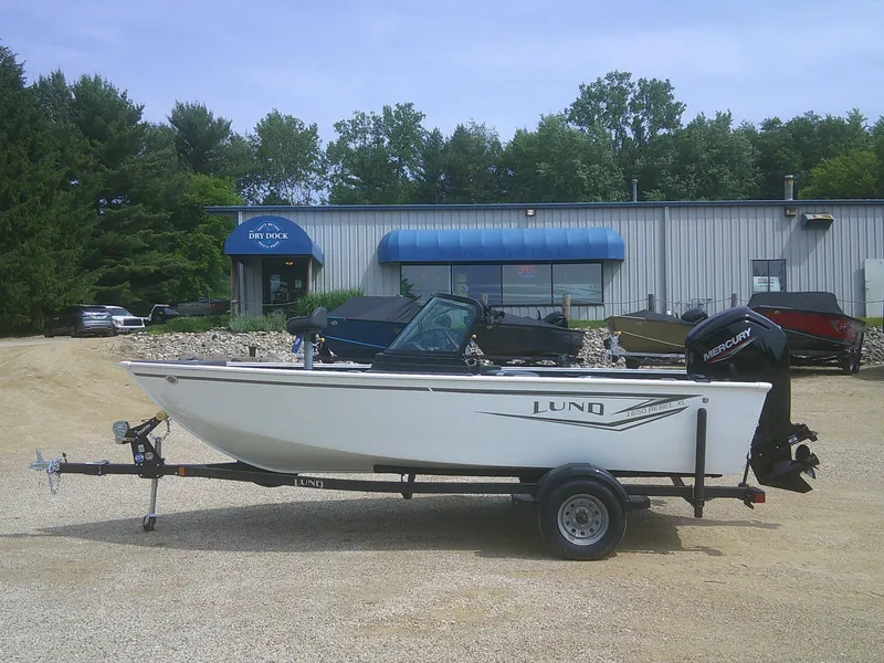 The Image of 2024 Lund 1650 Rebel XL Sport boat on trailer outside dealership. - 1