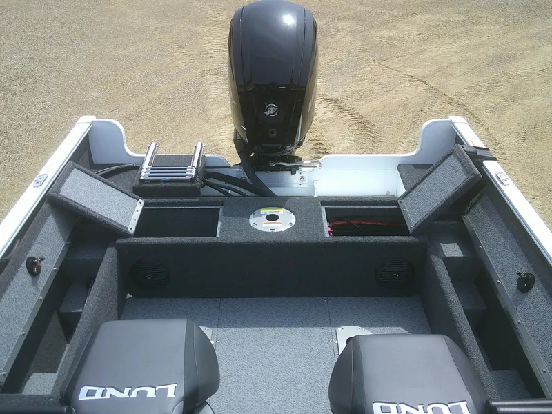 Slide: The Image of 2024 Lund 1650 Rebel XL Sport boat interior with motor and storage compartments. - 13