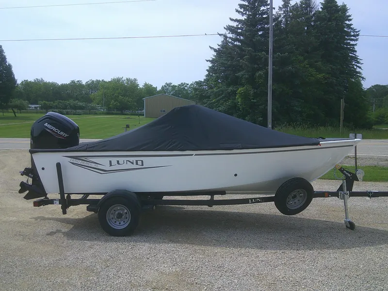 Slide: The Image of 2024 Lund 1650 Rebel XL Sport boat on trailer with cover, parked outdoors. - 17