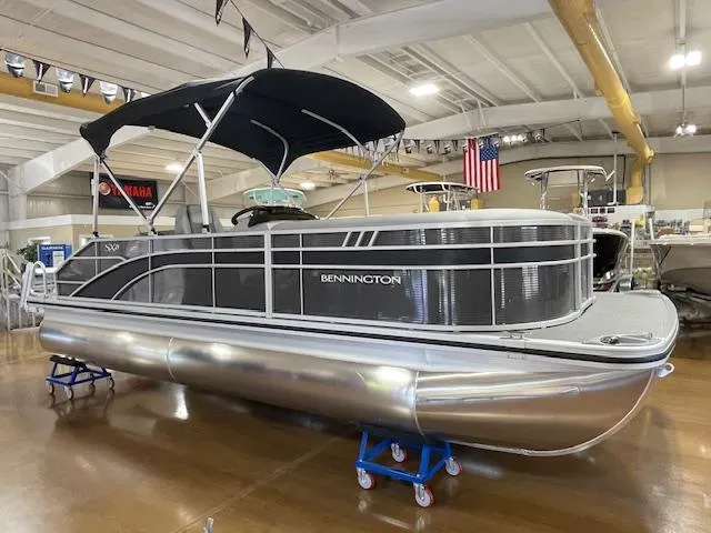 The Image of 2024 Bennington 21SXSB pontoon boat displayed indoors with black canopy. - 0