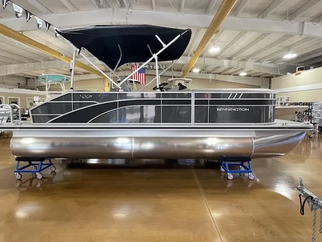 Slide: The Image of 2024 Bennington 21SXSB pontoon boat displayed indoors on stands. - 2