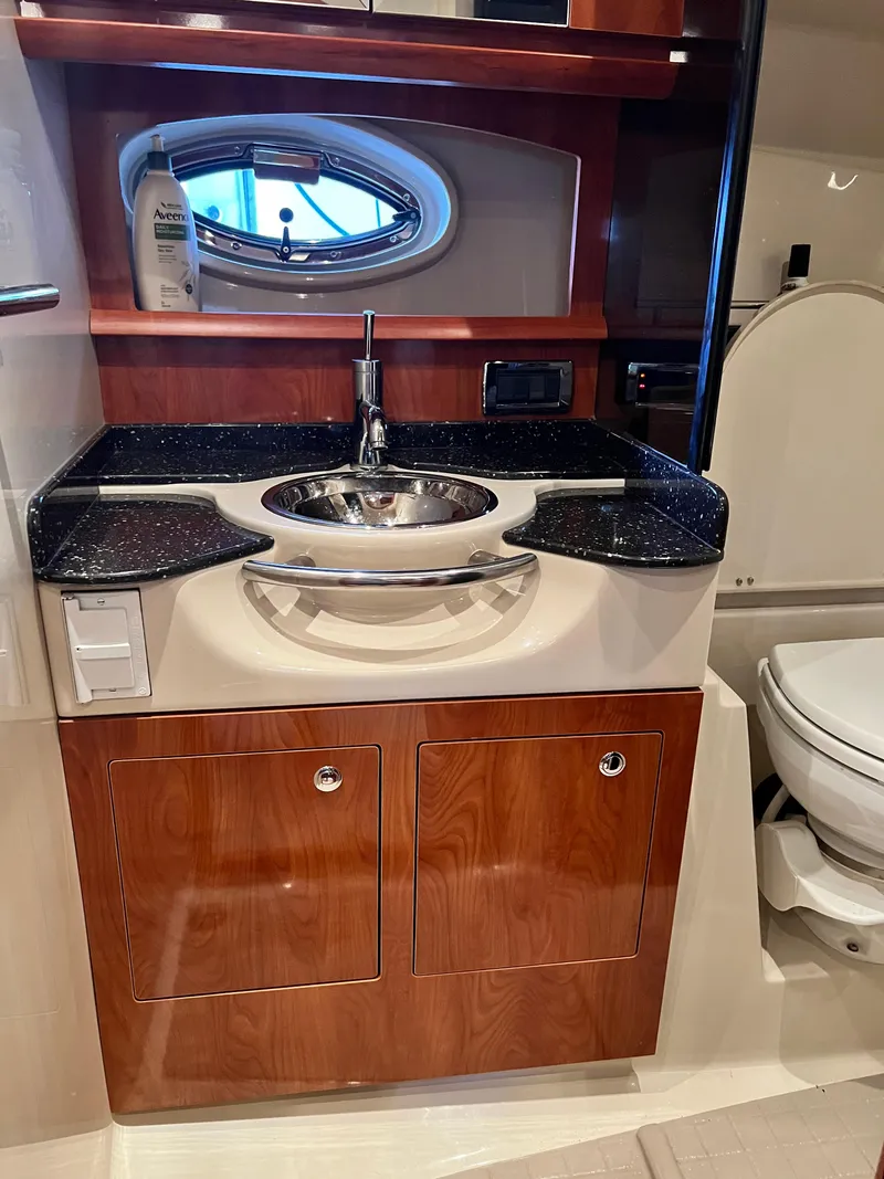 Slide: The Image of 2007 Four Winns 358 Vista bathroom with sink, wooden cabinets, and porthole window. - 19