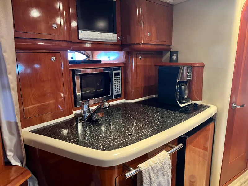 Slide: The Image of 2007 Four Winns 358 Vista yacht kitchen with microwave, coffee maker, and wooden cabinetry. - 23