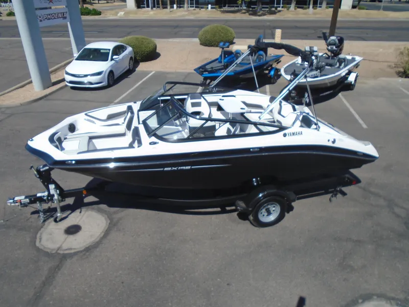 Slide: The Image of 2024 Yamaha Boats SX195 on trailer in parking lot, black and white design. - 14