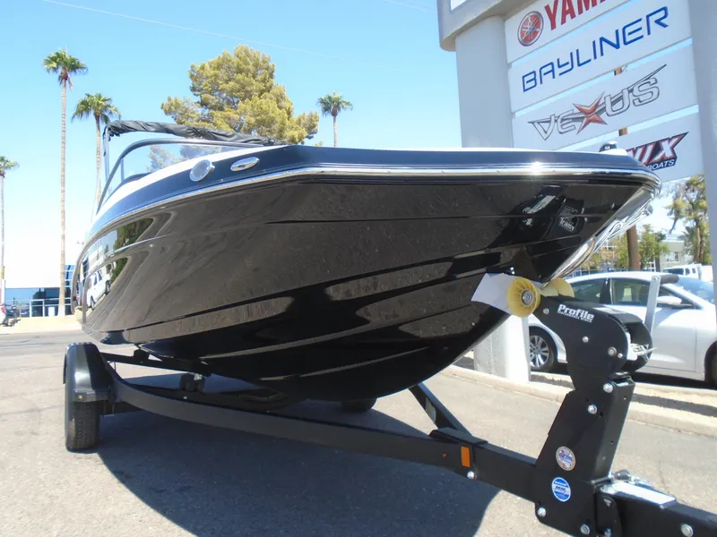 Slide: The Image of 2024 Yamaha Boats SX195 on trailer, displayed outdoors near dealership signs. - 3