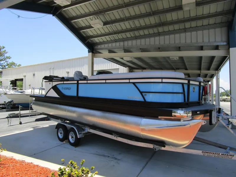 Slide: The Image of 2024 Sweetwater Entertainment SW 2286 MT pontoon boat on a trailer under a metal canopy. - 9