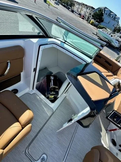 Slide: The Image of 2024 Four Winns HD3 OB boat interior with open storage compartment and tan seating. - 6