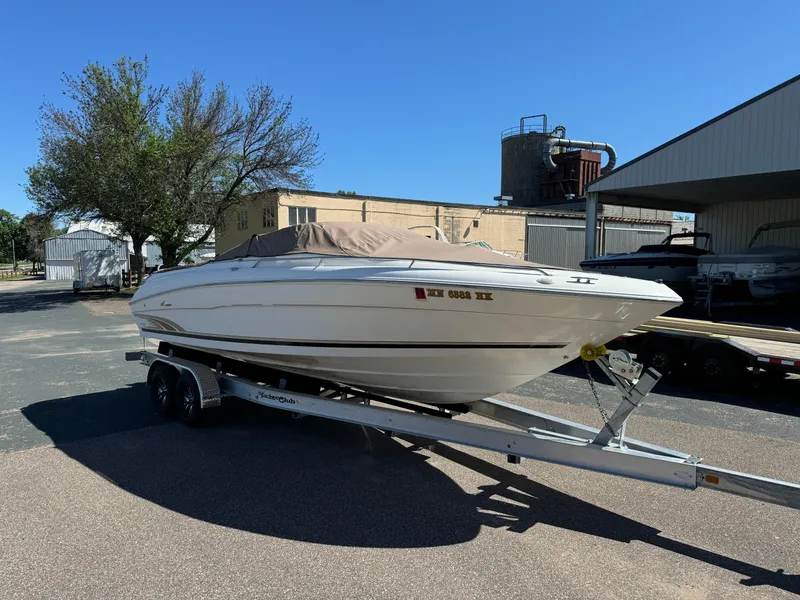 Slide: The Image of 1996 Sea Ray 260 Bow Rider on trailer, parked outdoors under clear blue sky. - 11