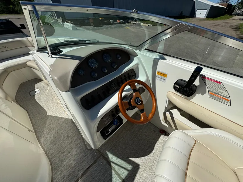 Slide: The Image of 1996 Sea Ray 260 Bow Rider dashboard with wooden steering wheel and beige seating. - 15