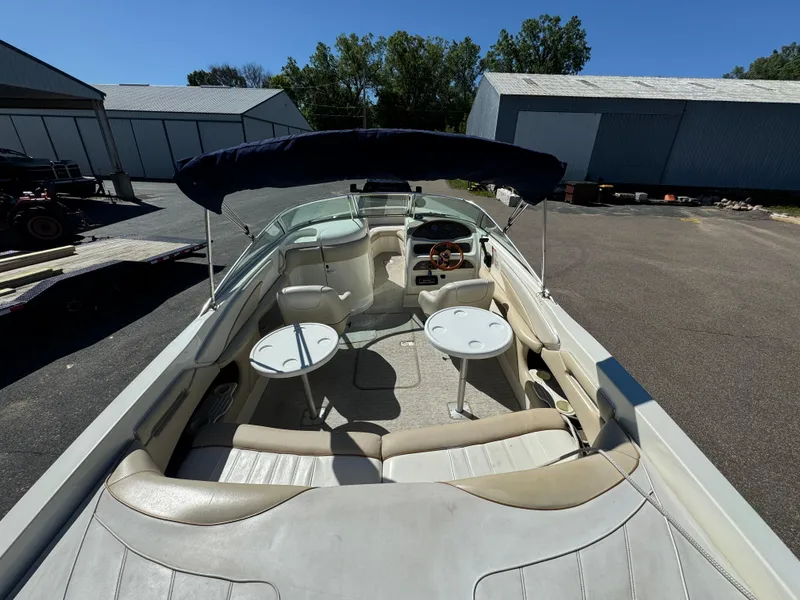 Slide: The Image of 1996 Sea Ray 260 Bow Rider boat with seating and tables, parked outdoors. - 22