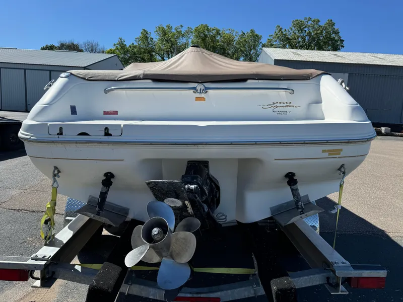 Slide: The Image of 1996 Sea Ray 260 Bow Rider on trailer, covered, with visible propeller and outdoor storage setting. - 8